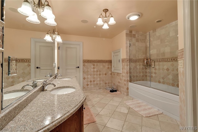 bathroom featuring bath / shower combo with glass door, tile walls, vanity, and an inviting chandelier