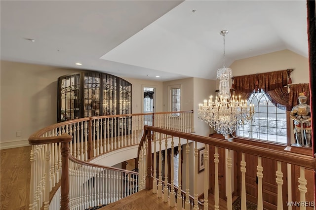 corridor featuring hardwood / wood-style flooring, lofted ceiling, and an inviting chandelier