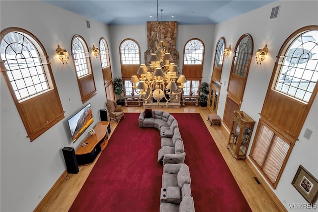 living room featuring a towering ceiling, light hardwood / wood-style floors, and a chandelier