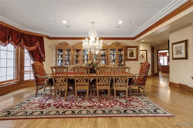 dining area with ornamental molding, a healthy amount of sunlight, hardwood / wood-style floors, and a notable chandelier