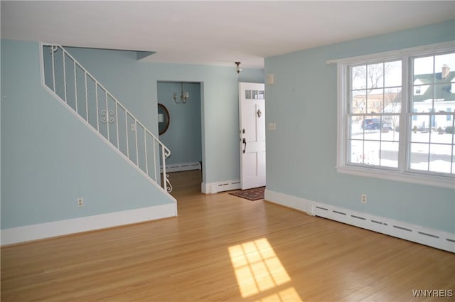 interior space featuring hardwood / wood-style flooring, a baseboard heating unit, and a chandelier