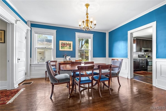 dining space with dark hardwood / wood-style flooring, ornamental molding, and an inviting chandelier