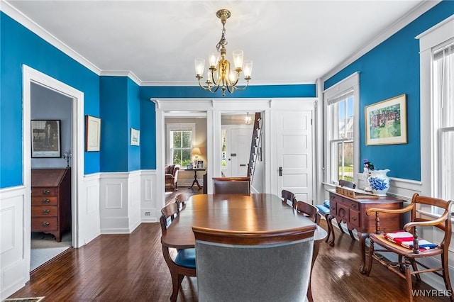 dining space featuring ornamental molding, dark wood-type flooring, and a notable chandelier