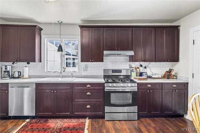 kitchen featuring appliances with stainless steel finishes, dark hardwood / wood-style floors, sink, and hanging light fixtures