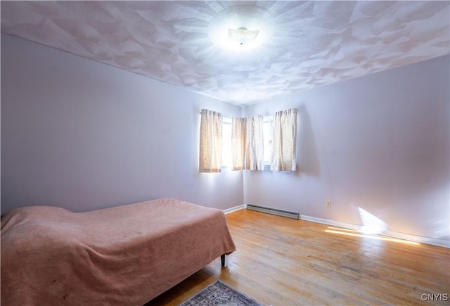 bedroom with baseboard heating and light hardwood / wood-style floors