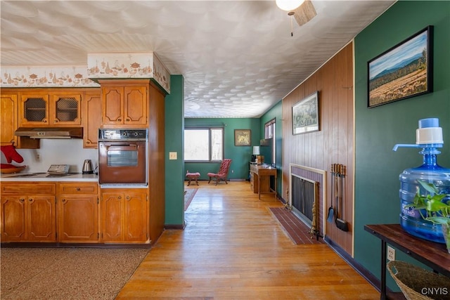 kitchen featuring wood walls, oven, and light wood-type flooring