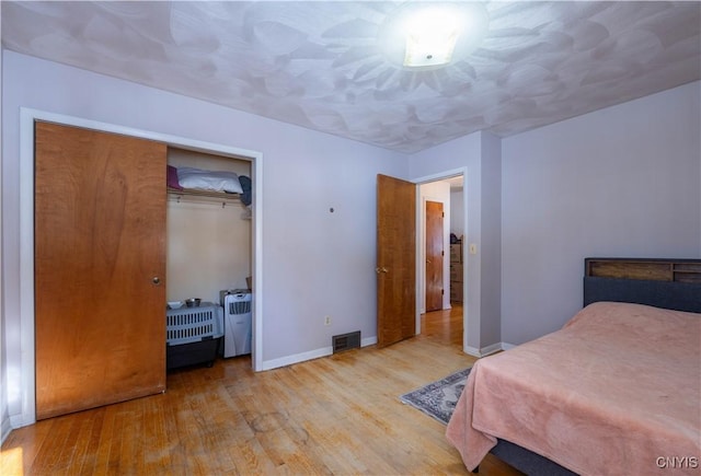 bedroom with light hardwood / wood-style floors and a closet