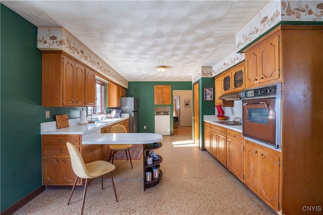 kitchen with white gas stovetop, stainless steel fridge, and oven