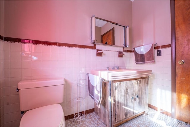 bathroom with vanity, tile patterned floors, tile walls, and toilet