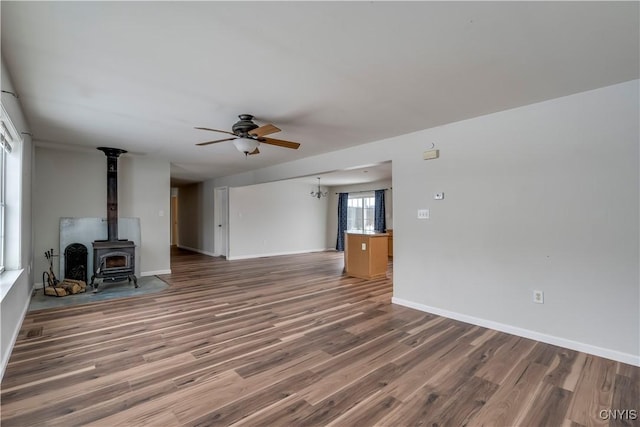 17200 Evans Rd, Hounsfield, NY 13634 - unfurnished living room with baseboards, a wood stove, ceiling fan, and wood finished floors