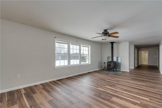 17200 Evans Rd, Hounsfield, NY 13634 - unfurnished living room with a wood stove, baseboards, a ceiling fan, and wood finished floors