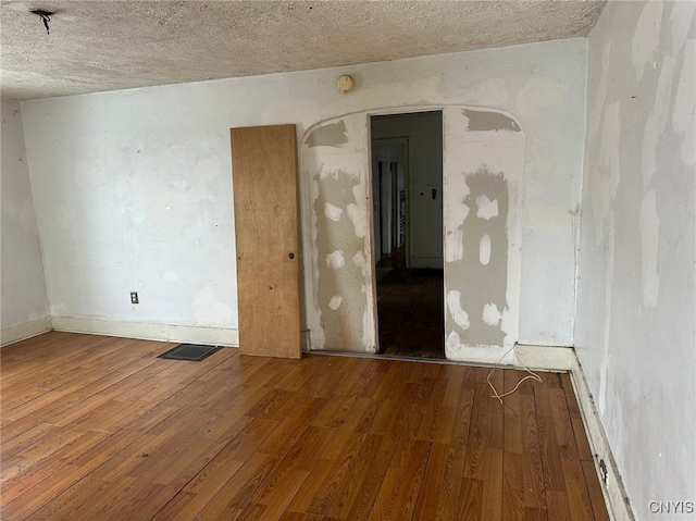 empty room with wood-type flooring and a textured ceiling