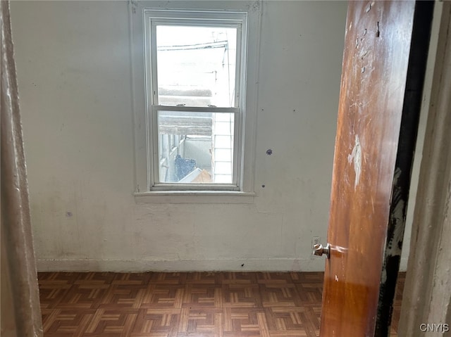 unfurnished room with a healthy amount of sunlight and dark parquet floors