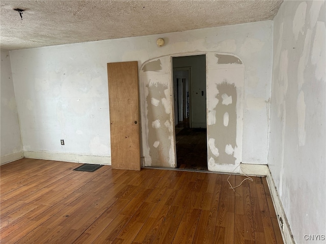 empty room featuring wood-type flooring and a textured ceiling