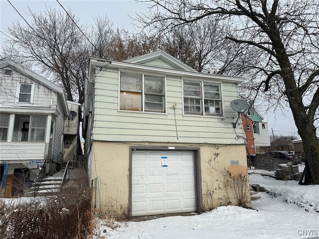 snow covered property with a garage