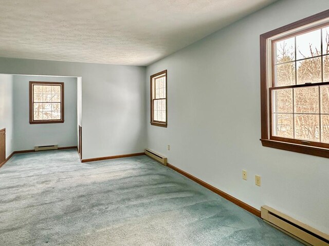 carpeted spare room with a baseboard radiator and a textured ceiling