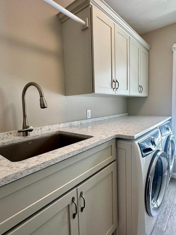 laundry room with cabinets, sink, washer and dryer, a textured ceiling, and hardwood / wood-style floors