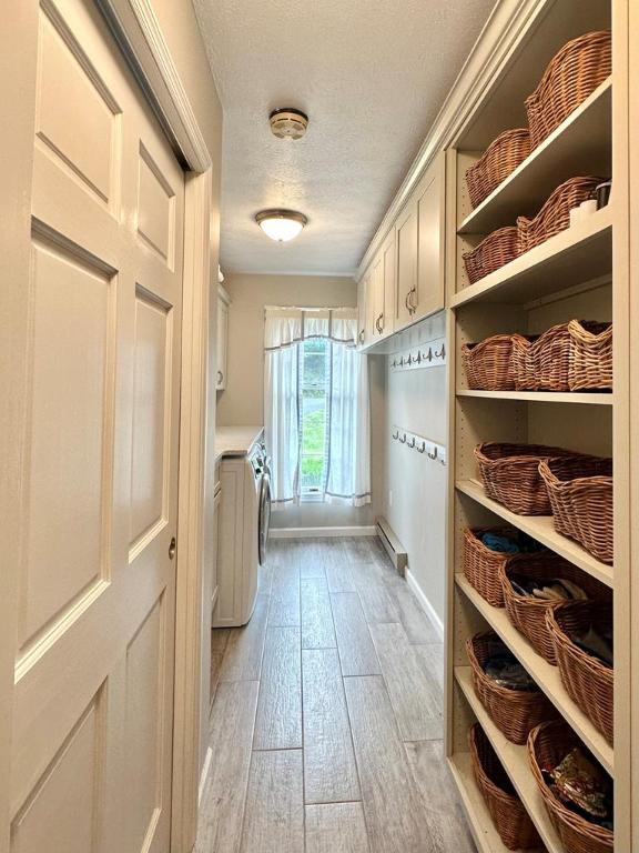 mudroom featuring independent washer and dryer, light hardwood / wood-style flooring, and a textured ceiling