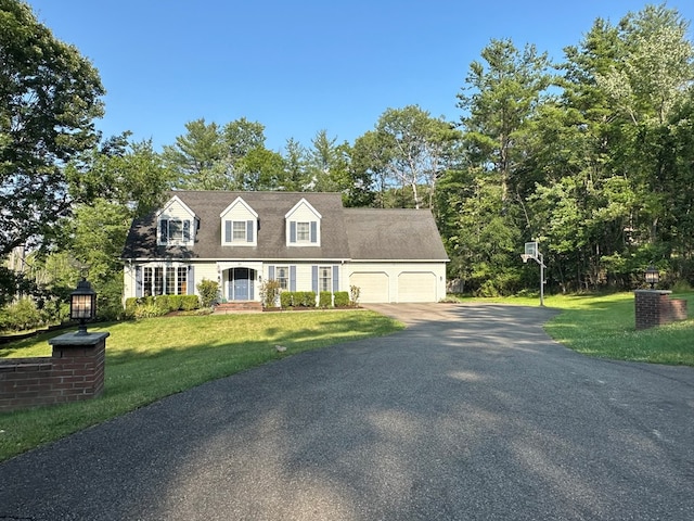 cape cod house featuring a front yard and a garage