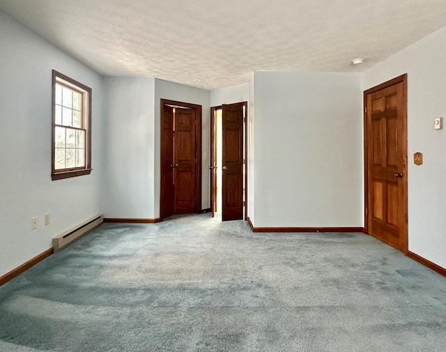 carpeted empty room featuring a textured ceiling and baseboard heating