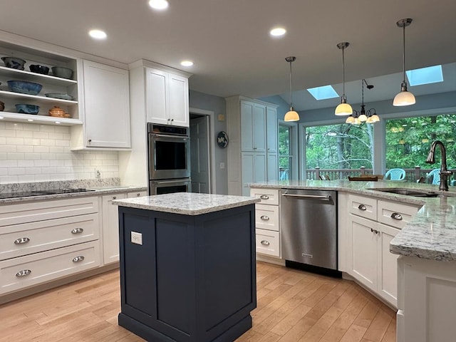 kitchen with sink, a skylight, white cabinets, and stainless steel appliances