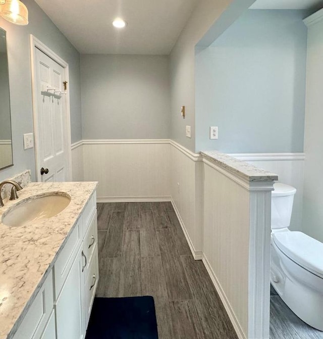 bathroom with toilet, vanity, and wood-type flooring