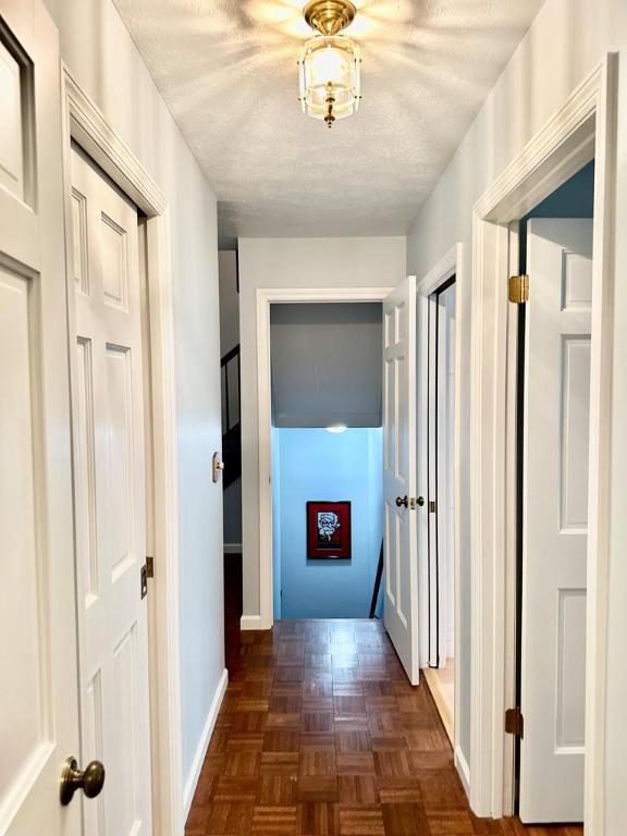 hallway featuring a textured ceiling and dark parquet flooring