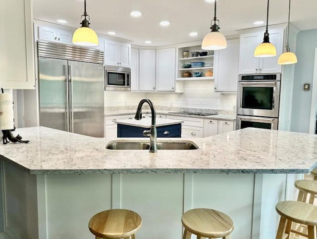 kitchen with built in appliances, decorative light fixtures, white cabinetry, and a breakfast bar