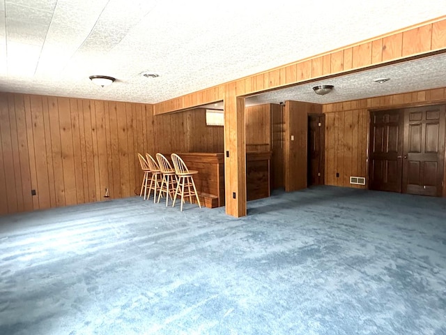 unfurnished room featuring carpet floors, indoor bar, and wooden walls