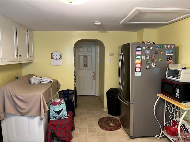 kitchen featuring stainless steel refrigerator and white cabinets