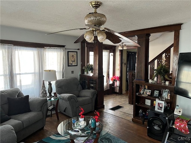 living room with hardwood / wood-style floors, ornate columns, a textured ceiling, and ceiling fan