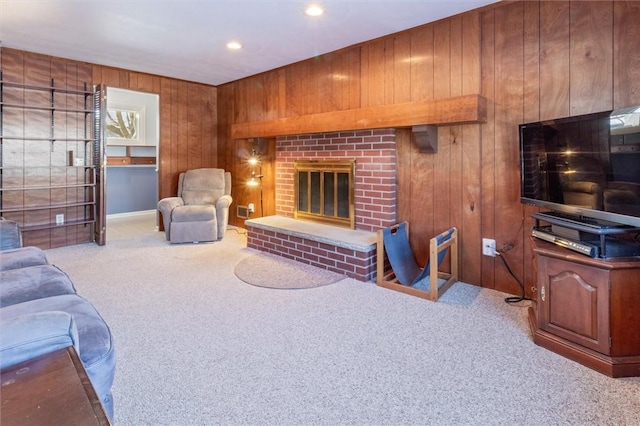 carpeted living room with a fireplace and wood walls