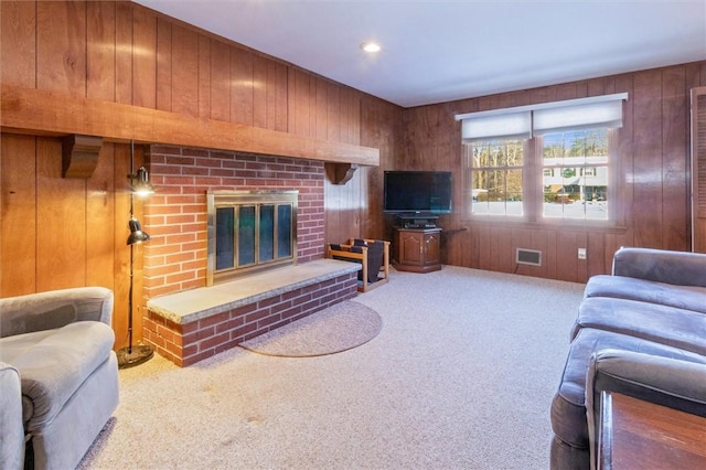 carpeted living room with a fireplace and wood walls