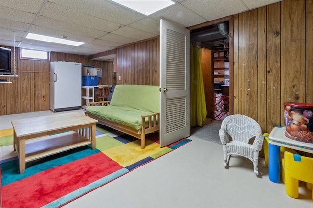 living area featuring a paneled ceiling and wood walls