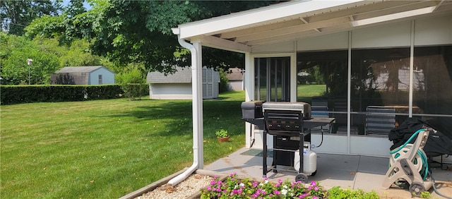 view of patio featuring a sunroom, a grill, and a storage unit