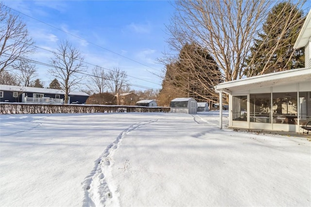 yard layered in snow featuring a sunroom