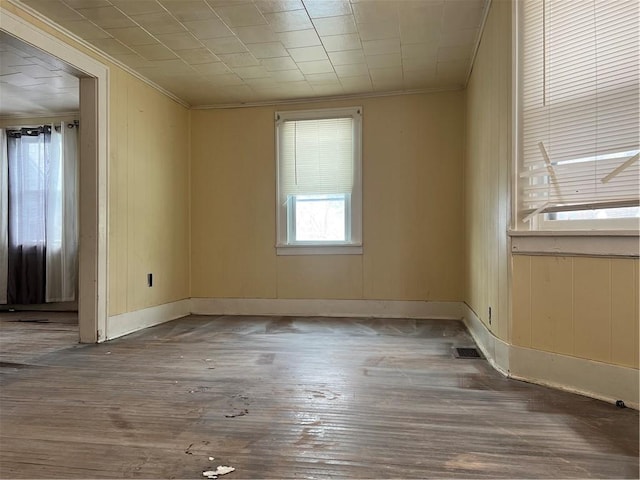 empty room with hardwood / wood-style flooring, ornamental molding, and wooden walls