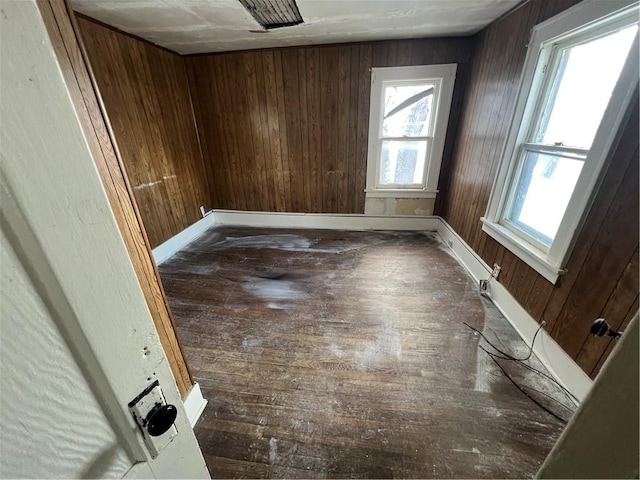 unfurnished room featuring wooden walls and dark hardwood / wood-style floors