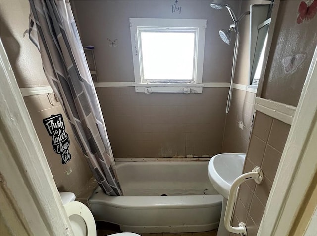 bathroom featuring tile walls, shower / bath combo, and toilet