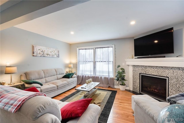 living room with a tile fireplace and light wood-type flooring