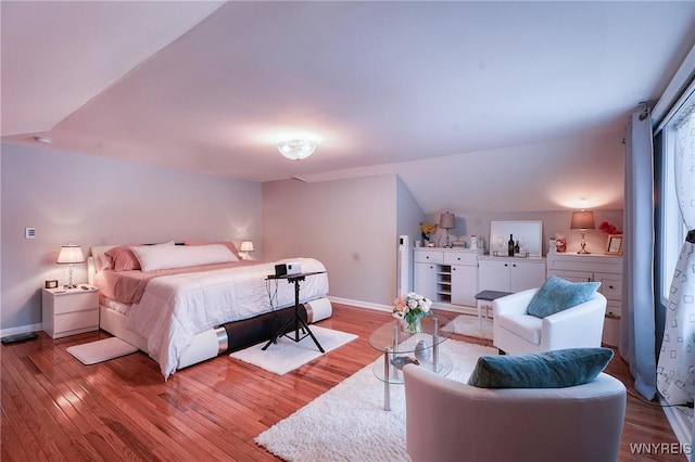 bedroom with vaulted ceiling and light wood-type flooring