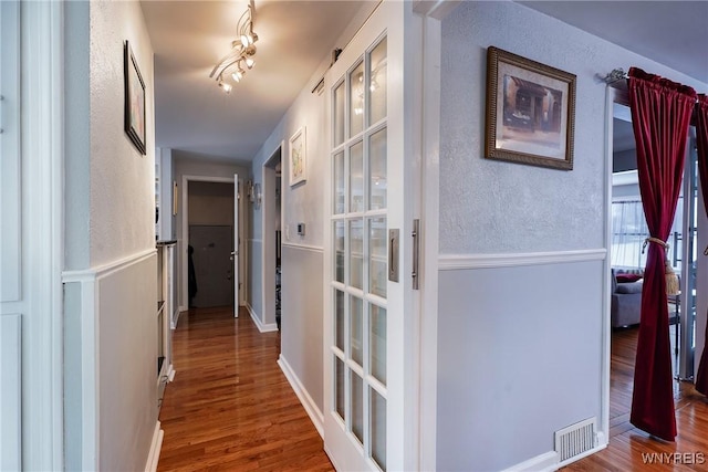 hall with rail lighting and hardwood / wood-style floors