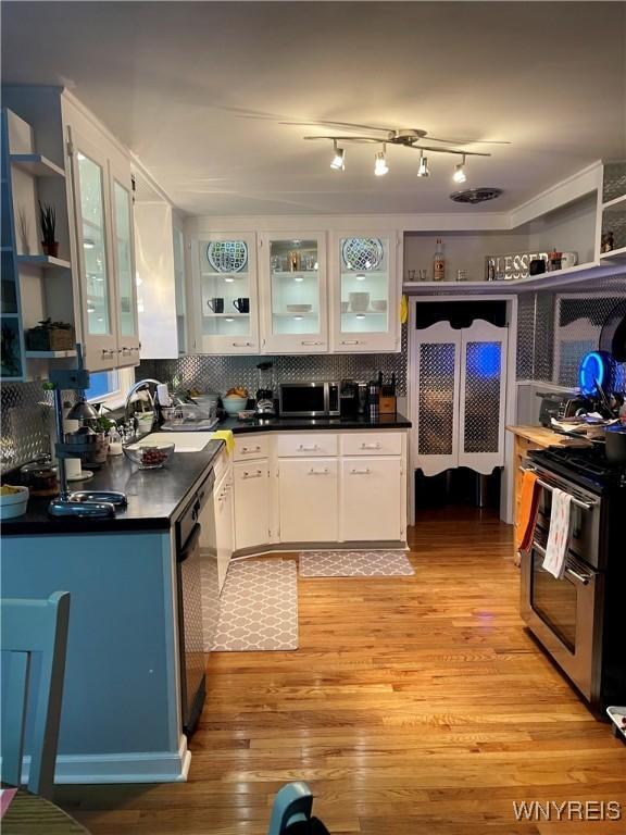 kitchen with stainless steel appliances, sink, white cabinets, and light hardwood / wood-style flooring