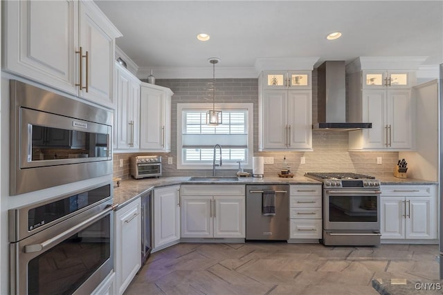 kitchen with appliances with stainless steel finishes, sink, light stone counters, wall chimney exhaust hood, and white cabinets