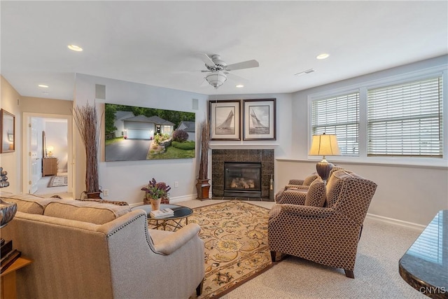 carpeted living room featuring a tiled fireplace and ceiling fan