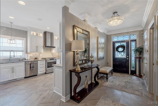 foyer entrance featuring a chandelier, sink, and ornamental molding