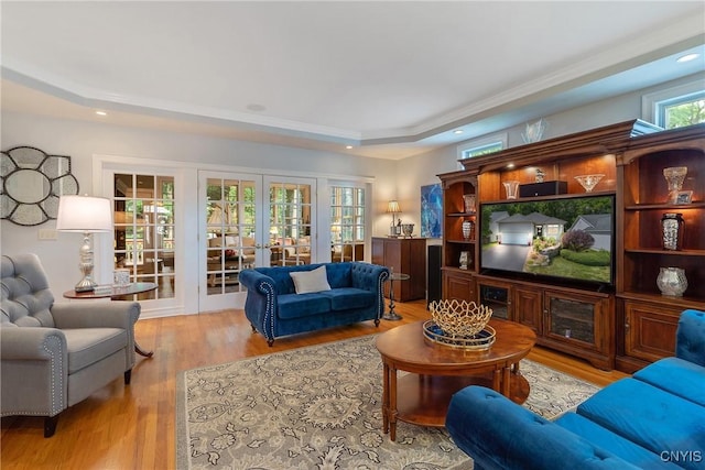 living room featuring light hardwood / wood-style floors, french doors, and a tray ceiling