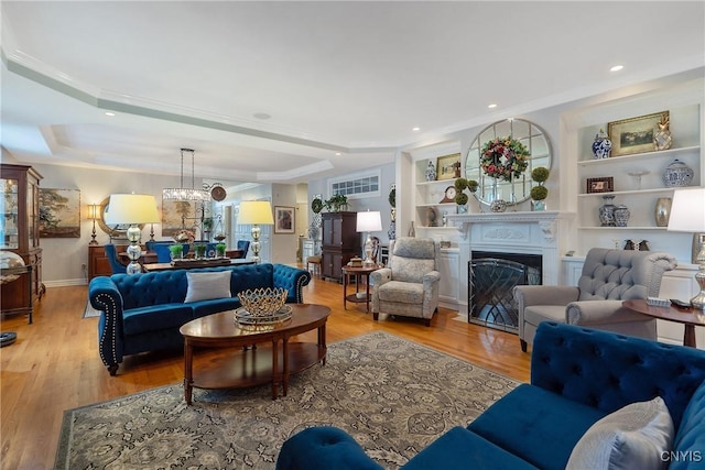 living room featuring a tray ceiling, light wood-type flooring, and crown molding