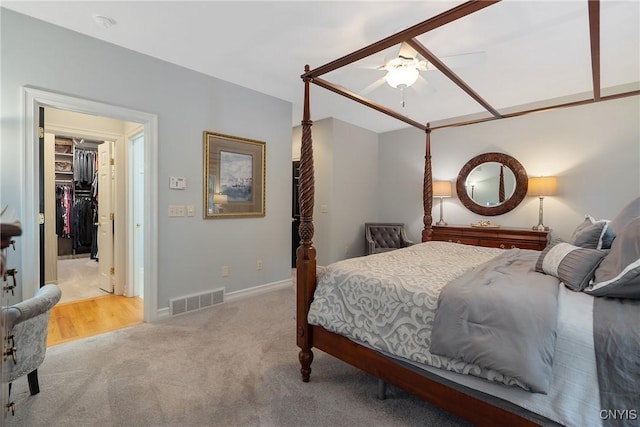 carpeted bedroom with ceiling fan and a spacious closet