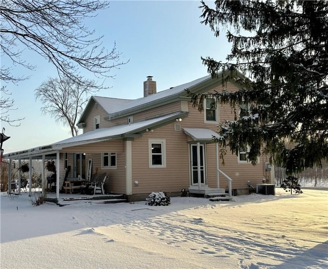 snow covered house featuring central air condition unit